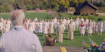 Movie still from “Midsommar” (2019), directed by Ari Aster – A group of people standing on top of a grass covered field; Extreme Wide shot, High angle