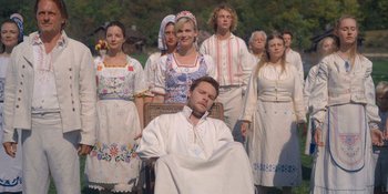Movie still from “Midsommar” (2019), directed by Ari Aster – A group of people standing around a man in a white shirt; Wide shot, High angle