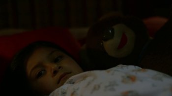 Movie still from “Narcos” (2015), created by Chris Brancato – A little girl laying in a bed next to a teddy bear; Close Up shot, High angle