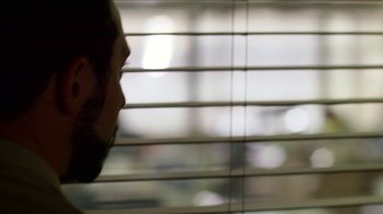 Movie still from “Narcos” (2015), created by Chris Brancato – A man looking out of a window through blinds; Extreme Close Up shot, Over the shoulder angle