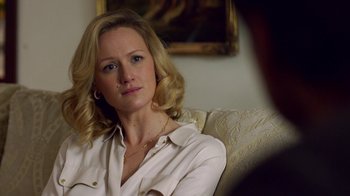 Movie still from “Narcos” (2015), created by Chris Brancato – A woman sitting on a couch in front of a painting; Close Up shot, Over the shoulder angle