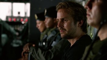 Movie still from “Narcos” (2015), created by Chris Brancato – A man in a black shirt is looking at the camera; Close Up shot, Over the shoulder angle