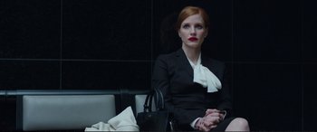 Movie still from “Miss Sloane” (2016), directed by John Madden – A woman sitting in a chair wearing a black suit; Medium shot, Low angle