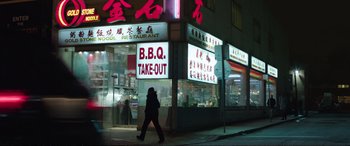 Movie still from “Miss Sloane” (2016), directed by John Madden – A person walking in front of a restaurant at night; Wide shot, High angle