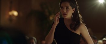 Movie still from “Miss Sloane” (2016), directed by John Madden – A woman talking on a cell phone while standing next to a table; Close Up shot, Over the shoulder angle