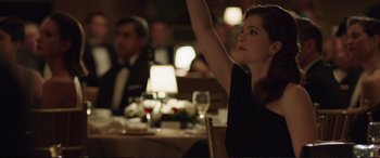 Movie still from “Miss Sloane” (2016), directed by John Madden – A woman sitting at a table with a glass of wine in front of her; Medium shot, Over the shoulder angle