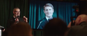 Movie still from “Miss Sloane” (2016), directed by John Madden – A man is giving a speech in front of a television; Close Up shot, Over the shoulder angle