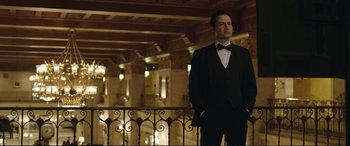 Movie still from “Miss Sloane” (2016), directed by John Madden – A man in a tuxedo standing in front of a railing; Medium shot, Low angle