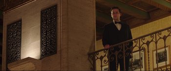 Movie still from “Miss Sloane” (2016), directed by John Madden – A man in a tuxedo standing on a railing next to a railing; Medium shot, Low angle