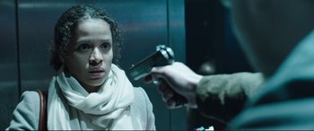 Movie still from “Miss Sloane” (2016), directed by John Madden – A person holding a gun in front of a woman; Close Up shot, Over the shoulder angle