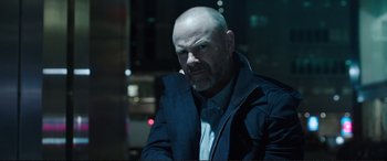 Movie still from “Miss Sloane” (2016), directed by John Madden – A man with a shaved head and a jacket; Close Up shot, Low angle