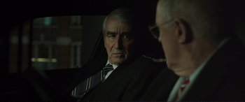 Movie still from “Miss Sloane” (2016), directed by John Madden – An older man wearing a suit and tie looking at the camera; Close Up shot, Over the shoulder angle