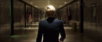 Movie still from “Miss Sloane” (2016), directed by John Madden – A woman in a black suit walking down a hall way; Medium shot, Over the shoulder angle