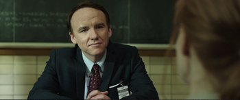 Movie still from “Miss Sloane” (2016), directed by John Madden – A man in a suit and tie sitting in front of a brick wall; Close Up shot, Over the shoulder angle