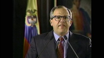 Movie still from “Narcos” (2015), created by Chris Brancato – A person wearing a suit and glasses; Close Up shot, Low angle