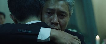 Movie still from “Night in Paradise” (2020), directed by Park Hoon-jung – A man in a suit hugging another man in a suit; Close Up shot, Over the shoulder angle