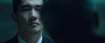 Movie still from “Night in Paradise” (2020), directed by Park Hoon-jung – A person wearing a suit and tie; Extreme Close Up shot, Over the shoulder angle