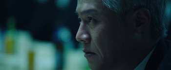 Movie still from “Night in Paradise” (2020), directed by Park Hoon-jung – A man's face in a dark room; Extreme Close Up shot, Low angle