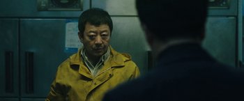 Movie still from “Night in Paradise” (2020), directed by Park Hoon-jung – A man in a yellow jacket looking at himself in the mirror; Medium shot, Low angle