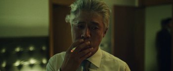 Movie still from “Night in Paradise” (2020), directed by Park Hoon-jung – A man in a white shirt and tie smoking a cigarette; Close Up shot, Low angle