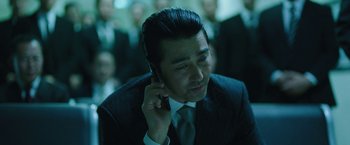 Movie still from “Night in Paradise” (2020), directed by Park Hoon-jung – A man in a suit and tie talking on a cell phone; Close Up shot, Low angle