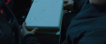 Movie still from “Night in Paradise” (2020), directed by Park Hoon-jung – A person holding a stack of books in their hands; Extreme Close Up shot, Overhead angle