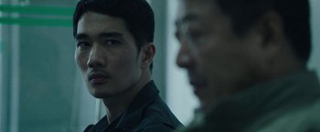 Movie still from “Night in Paradise” (2020), directed by Park Hoon-jung – Two men are looking at each other in a room; Close Up shot, Over the shoulder angle