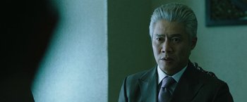 Movie still from “Night in Paradise” (2020), directed by Park Hoon-jung – A man in a suit and tie looking at the camera; Close Up shot, Low angle