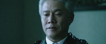 Movie still from “Night in Paradise” (2020), directed by Park Hoon-jung – A person wearing a suit and tie; Close Up shot, Low angle