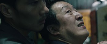 Movie still from “Night in Paradise” (2020), directed by Park Hoon-jung – A man with his face close to the face of another man; Extreme Close Up shot, Low angle