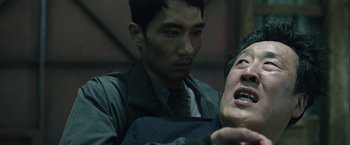 Movie still from “Night in Paradise” (2020), directed by Park Hoon-jung – A man is holding a knife in his mouth; Close Up shot, Over the shoulder angle