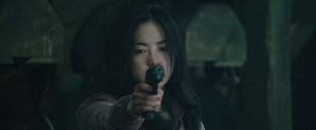 Movie still from “Night in Paradise” (2020), directed by Park Hoon-jung – A woman holding a gun in her hand; Close Up shot, Over the shoulder angle