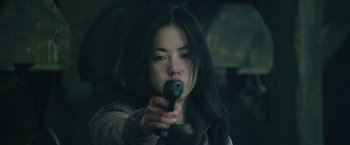 Movie still from “Night in Paradise” (2020), directed by Park Hoon-jung – A woman holding a gun in her hand; Close Up shot, Low angle