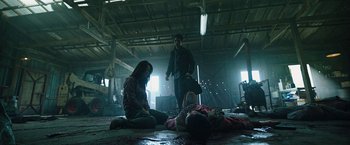 Movie still from “Night in Paradise” (2020), directed by Park Hoon-jung – A man and a woman sitting on the ground next to a dead body; Wide shot, Low angle