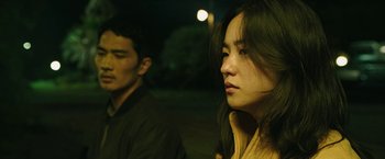 Movie still from “Night in Paradise” (2020), directed by Park Hoon-jung – A man and a woman standing next to each other; Close Up shot, Over the shoulder angle