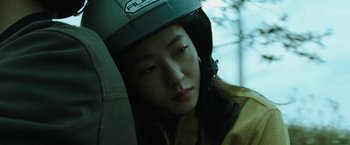 Movie still from “Night in Paradise” (2020), directed by Park Hoon-jung – A young woman wearing a helmet while sitting in a car; Close Up shot, High angle