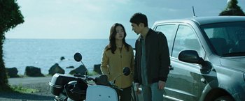 Movie still from “Night in Paradise” (2020), directed by Park Hoon-jung – A man and a woman standing next to a motorcycle; Medium shot, Low angle