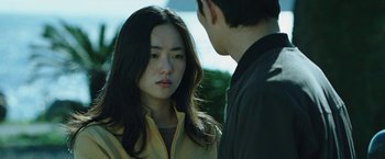 Movie still from “Night in Paradise” (2020), directed by Park Hoon-jung – A young man and a young woman standing next to each other; Close Up shot, Over the shoulder angle