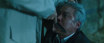 Movie still from “Night in Paradise” (2020), directed by Park Hoon-jung – A man with a knife in his mouth; Close Up shot, Over the shoulder angle