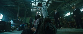 Movie still from “Night in Paradise” (2020), directed by Park Hoon-jung – A group of men standing around in a room; Wide shot, Low angle