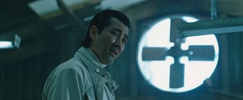 Movie still from “Night in Paradise” (2020), directed by Park Hoon-jung – A man in a white shirt is standing in front of a window; Close Up shot, Low angle