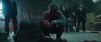 Movie still from “Night in Paradise” (2020), directed by Park Hoon-jung – A man is holding a knife over another man's head; Medium shot, Low angle