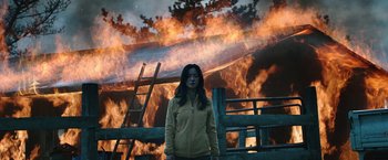 Movie still from “Night in Paradise” (2020), directed by Park Hoon-jung – A woman standing in front of a burning house; Wide shot, Low angle