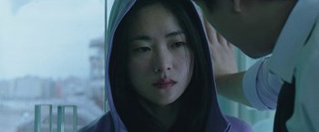 Movie still from “Night in Paradise” (2020), directed by Park Hoon-jung – A young asian woman wearing a hooded sweatshirt; Close Up shot, Over the shoulder angle