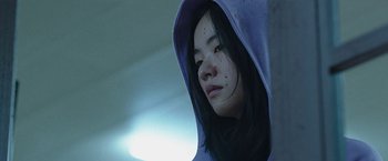 Movie still from “Night in Paradise” (2020), directed by Park Hoon-jung – A young woman wearing a hooded sweatshirt; Close Up shot, Low angle