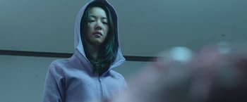 Movie still from “Night in Paradise” (2020), directed by Park Hoon-jung – A woman with green hair wearing a hooded sweatshirt; Close Up shot, Low angle
