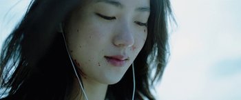 Movie still from “Night in Paradise” (2020), directed by Park Hoon-jung – A young woman wearing headphones with blood on her face; Extreme Close Up shot, Low angle
