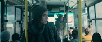Movie still from “No One Gets Out Alive” (2021), directed by Santiago Menghini – A woman in a hat and scarf riding a bus; Close Up shot, Over the shoulder angle