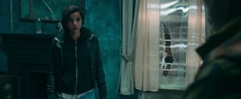 Movie still from “No One Gets Out Alive” (2021), directed by Santiago Menghini – A woman standing in front of an open window; Medium shot, Over the shoulder angle