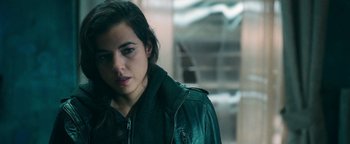 Movie still from “No One Gets Out Alive” (2021), directed by Santiago Menghini – A woman in a leather jacket looking at the camera; Close Up shot, Over the shoulder angle